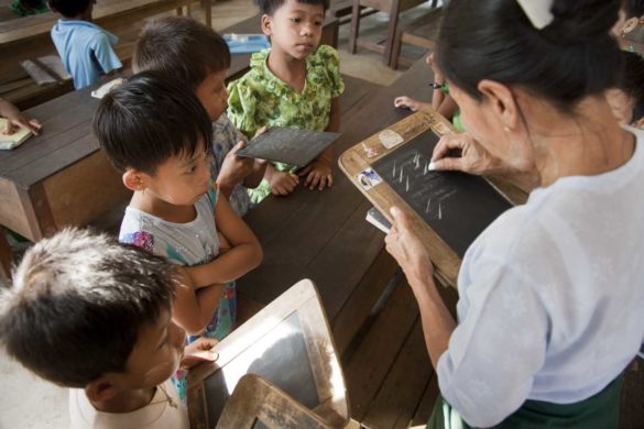 Daw Khin San Win (45) a teacher is teaching to children’s in classroom of Puzunchaung Primary School, Kungyangone, Yangon Region, Burma on 8 February 2012. Most of the fisherman and farmer family in this area was lost there everything by cyclone NARGIS in 2008. Fishermen’s and farmers are got financial support from Oxfam Novib by support Metta foundation for cultivation and fishing material.  Now they are stable in there daily  life and sending child’s to school for education.